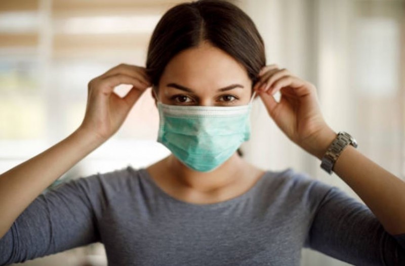 woman putting on non-medical mask